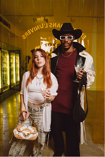 Stylish couple posing with drinks at fashion event