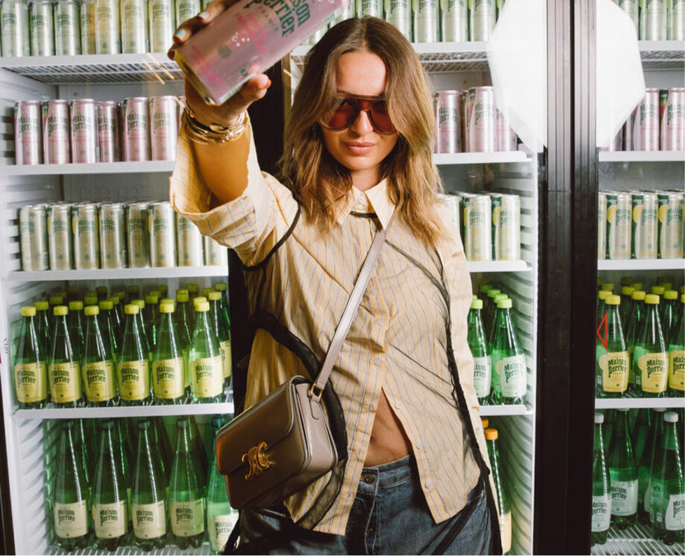 Woman holding sparkling water can in front of fridge